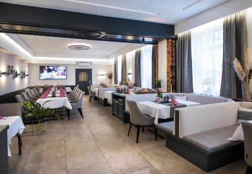 a restaurant with tables and chairs and a flat screen tv at Hotel Alexandra in Wels