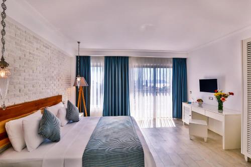 a bedroom with a bed and a desk with a television at Arnna Hotel in Kas