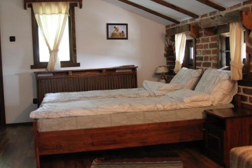 a bedroom with a wooden bed in a room at Guest House Shapkova Kushta in Delchevo