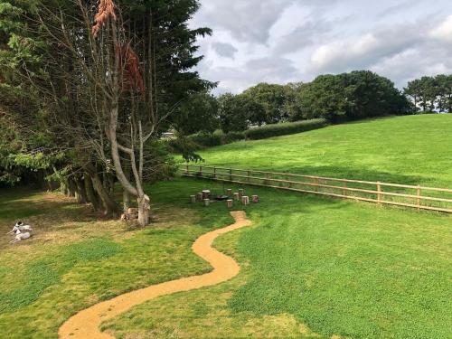a winding path in a field with a fence at Deer Den timber clad cabin with hot tub, up private lane in Cullompton