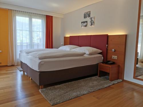 a bedroom with a large bed with a red headboard at Parkhotel Schoenegg in Grindelwald