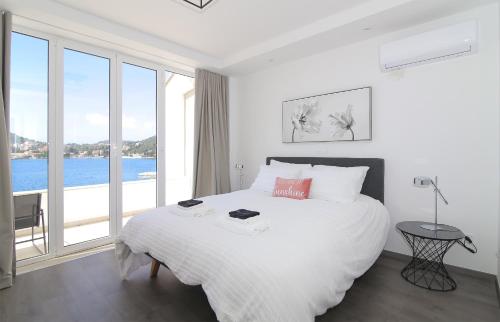 - une chambre blanche avec un grand lit et une grande fenêtre dans l'établissement Seaside Apartment M Zaton 4 -SeaView and Parking, à Zaton