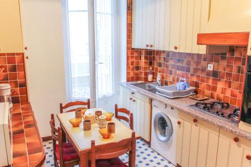 une cuisine avec une table et une machine à laver dans l'établissement Nice Large 2BR Sunny 20 Meter Terrace Parking Beach Shops, à Nice
