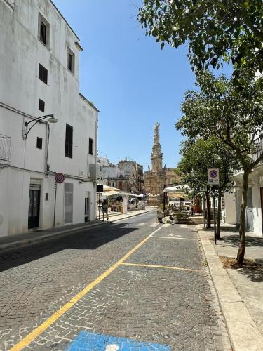 an empty city street with a clock tower in the distance at Dimora L’Antico Bijou in Ostuni