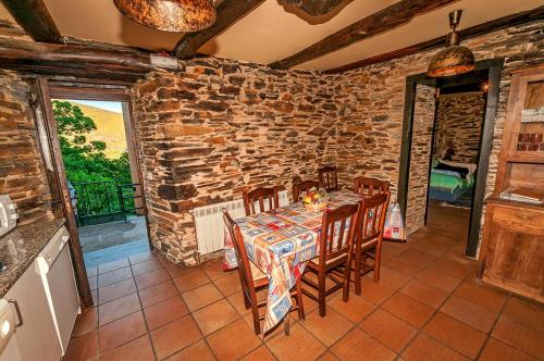 a dining room with a table and chairs and a stone wall at Casa Do Concello in Arnado