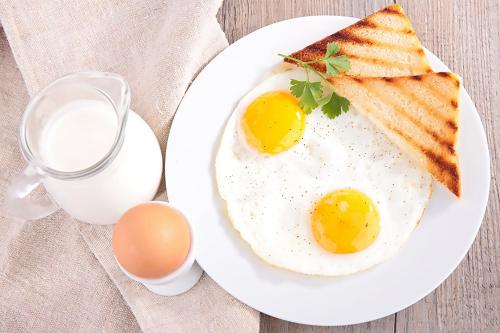 two eggs and toast on a plate with milk at Royal Continental Hotel in Lahore
