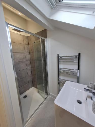 y baño con ducha y lavamanos. en Perfect Location 3 Bed Serviced apartment with Bike Storage for BPW. Close to Brecon Beacons, en Merthyr Tydfil