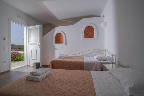 a bedroom with two beds and a large window at Casa Nostra Mykonos Boutique Rooms & Studios in Glastros