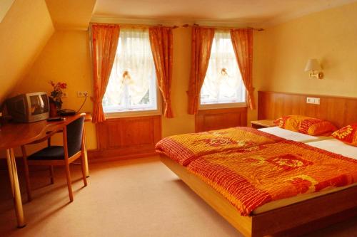 a bedroom with a bed and a desk and windows at Pension Webstuhl in Deizisau