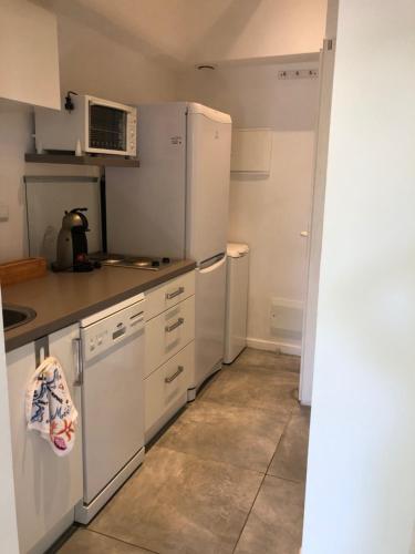 une cuisine avec des appareils électroménagers blancs et des armoires blanches dans l'établissement studio avec terrasse et jardin à 3 minutes à pied de la plage, à Canet