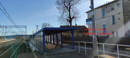 a bus stop at a train station next to a building at Apartament w spokojnej lokalizacji in Cieplewo