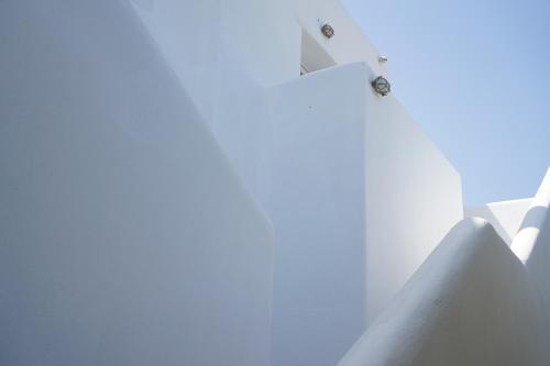 a white room with a light on the wall at Casa Nostra Mykonos Boutique Rooms & Studios in Glastros