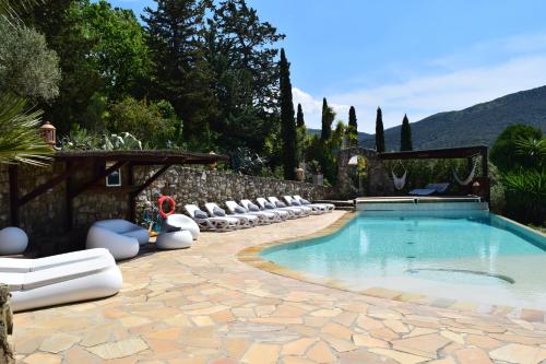 a swimming pool with chairs and a stone wall at Villa Le Agavi & Spa in Scarlino