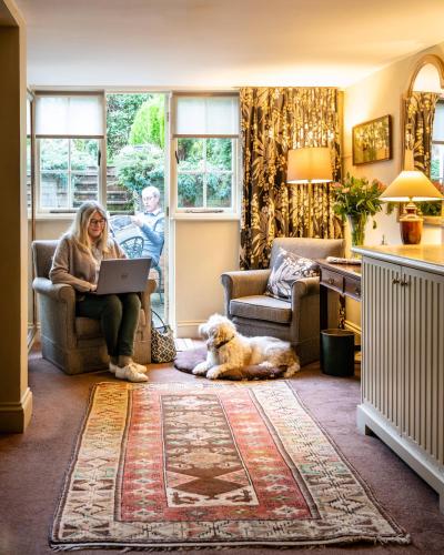 a woman sitting in a chair with a laptop and a dog at Luttrell Arms in Dunster