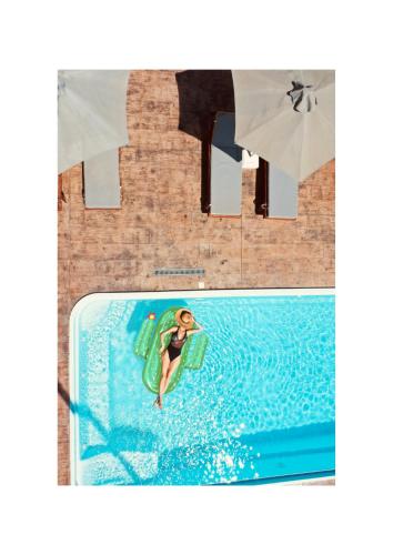 a woman in a pool on a inflatableogie board at Casa Nostra Mykonos Boutique Rooms & Studios in Glastros