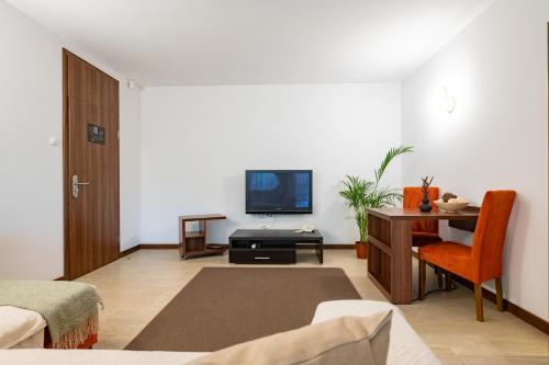 ein Wohnzimmer mit einem TV und einem Schreibtisch mit einem Stuhl in der Unterkunft Epico Seafront & Garden Apartments in Olimp