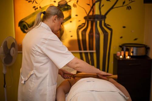 a woman is cutting a persons head with a bat at Bagińscy Spa in Pobierowo