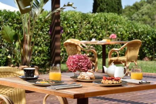 a wooden table with plates of food and orange juice at Argentario Lagoon Resort & Spa in Monte Argentario
