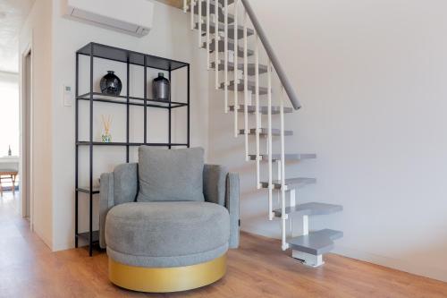 a living room with a chair next to a staircase at Bemyguest - Loft Guest House Jardim das Mães Charming in Viseu