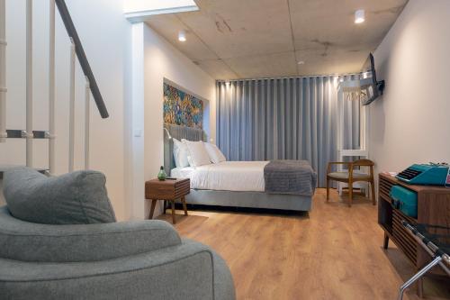 a bedroom with a bed and a couch and a tv at Bemyguest - Loft Guest House Jardim das Mães Charming in Viseu