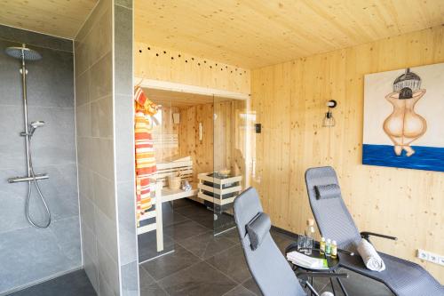 uma casa de banho com um chuveiro, uma mesa e 2 cadeiras em Holzhaus "Zum Schwarz'n" em Aurach am Hongar