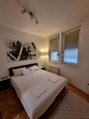 a bedroom with a white bed and two windows at Apartman Veselinovic Free PARKING in Vranje