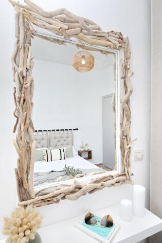 a mirror with a driftwood frame on top of a bed at Rania Residence in Skopelos Town