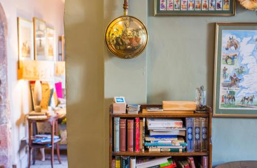 a book shelf with books and a clock on the wall at Luttrell Arms in Dunster