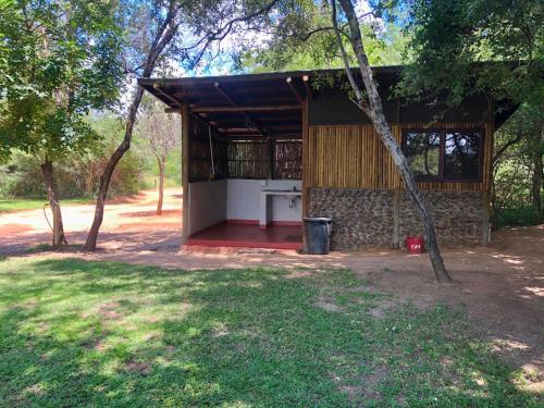 a small building with a porch and a tree at RiverDance Lodge in Mamono