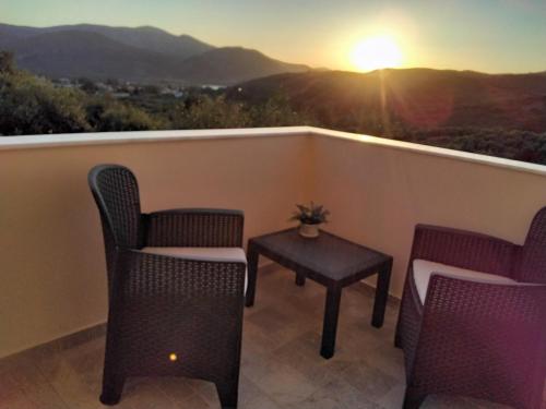 a balcony with chairs and a table and the sunset at Apartments Gonies - Artemis in Goníai