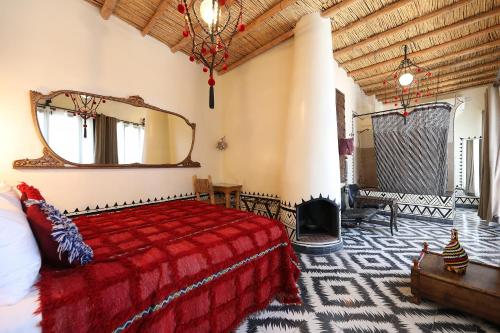 Riad Bindoo & Spa في مراكش: غرفة نوم بسرير احمر ومرآة