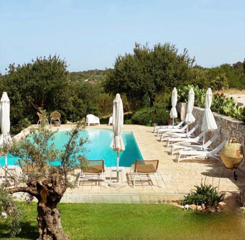 - une piscine avec des chaises longues et des parasols dans l'établissement Dimora Le Ginestre, à Fasano