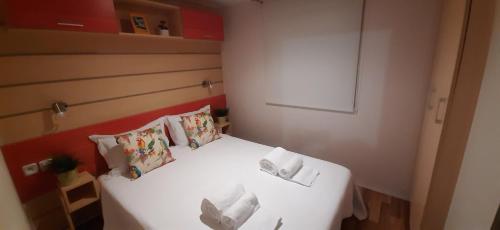 um pequeno quarto com uma cama branca e almofadas em Rota da vila-Quinta das Rãs em Foz do Sousa