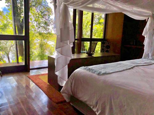 a bedroom with a bed and a large window at RiverDance Lodge in Mamono