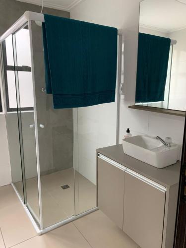 a bathroom with a glass shower and a sink at PALLADIUM APART SERVICE in São Vicente