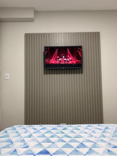 - une télévision sur un mur dans l'établissement PALLADIUM APART SERVICE, à São Vicente