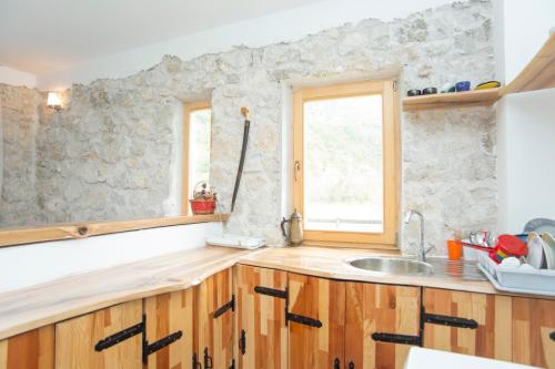 a kitchen with wooden cabinets and a stone wall at Exo Log Cottage in Jezero