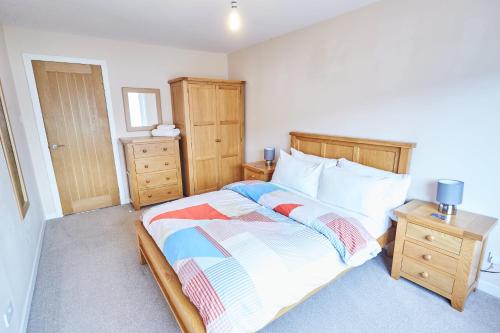 a bedroom with a large bed and a night stand at Etive, Beautiful Lochside Apartment with balcony in Fort William