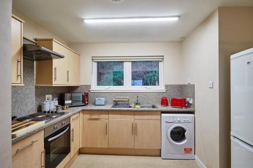 a kitchen with a washing machine and a sink at Etive, Beautiful Lochside Apartment with balcony in Fort William