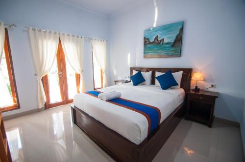 1 dormitorio con 1 cama grande con almohadas azules en The Dagan Bungalow en Nusa Penida