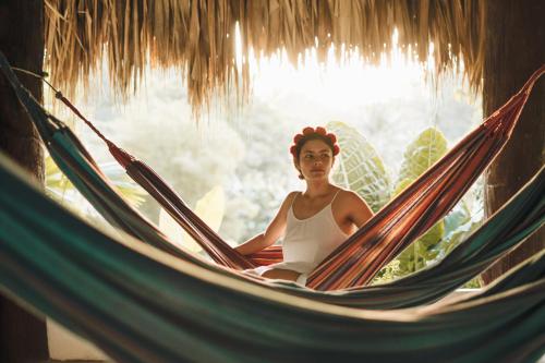 a woman is sitting in a hammock at Makenke Hostel By Los Colores Ecoparque in Doradal