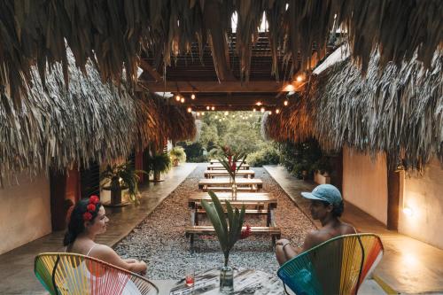 two people sitting in chairs in a restaurant at Makenke Hostel By Los Colores Ecoparque in Doradal