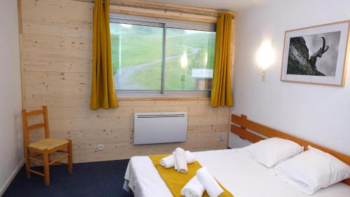 a bedroom with a bed and a window with yellow curtains at Le Balcon des Ecrins in Réallon