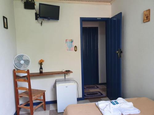 a room with a bed and a door with a fan at Pousada Estrada Real in Milho Verde