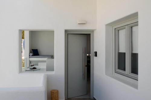 um quarto branco com uma porta e uma janela em Harmony Suites em Fira
