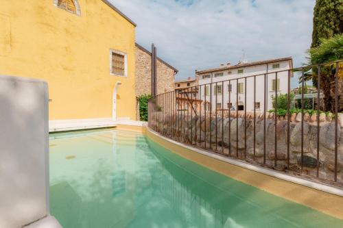 a pool of turquoise water next to a building at Residence Corte San Carlo in Colà di Lazise