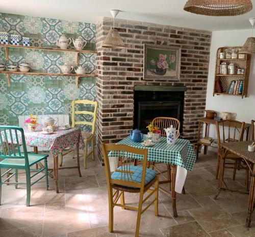 a living room with a table and chairs and a fireplace at Maison Léontine in Bernay