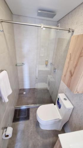 a bathroom with a white toilet and a shower at Toscana LOFT - Apartasuites in Bogotá