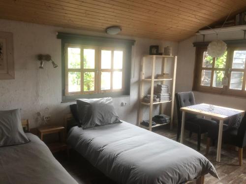 a bedroom with two beds and a table and windows at Bed & Breakfast Herkingen GR5 in Herkingen