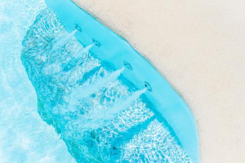 a blue raft in the water next to a beach at Sisula Country Hotel & SPA in Orosei
